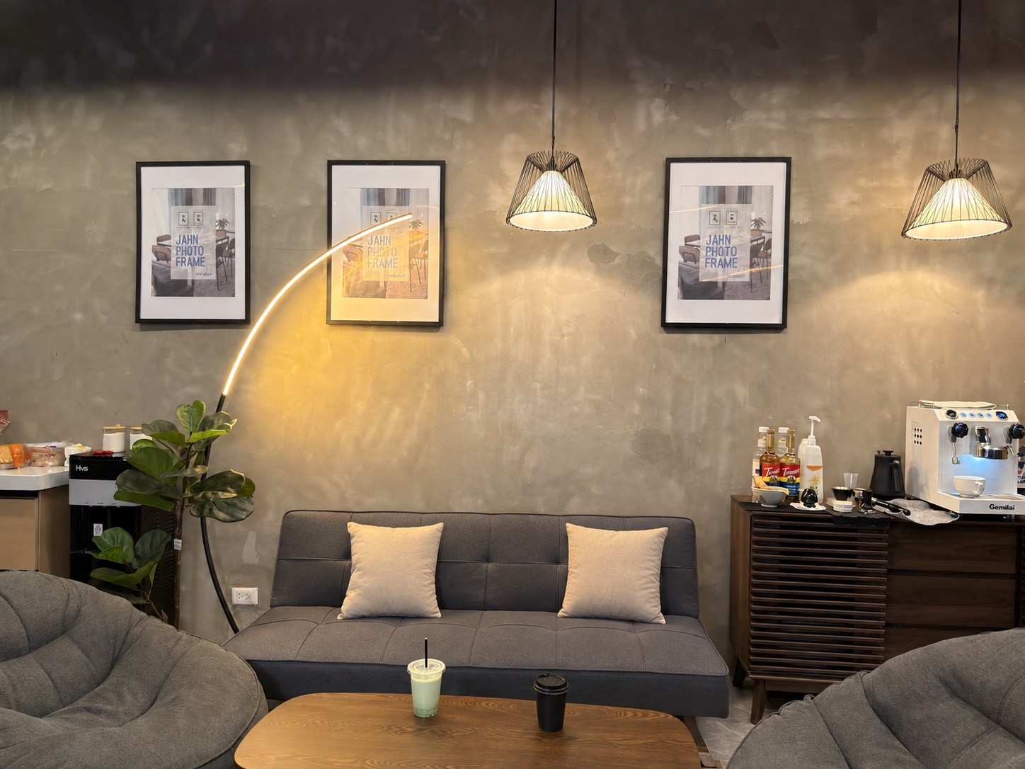 ARC lounge with gray sofas, warm pendant lights and a coffee bar